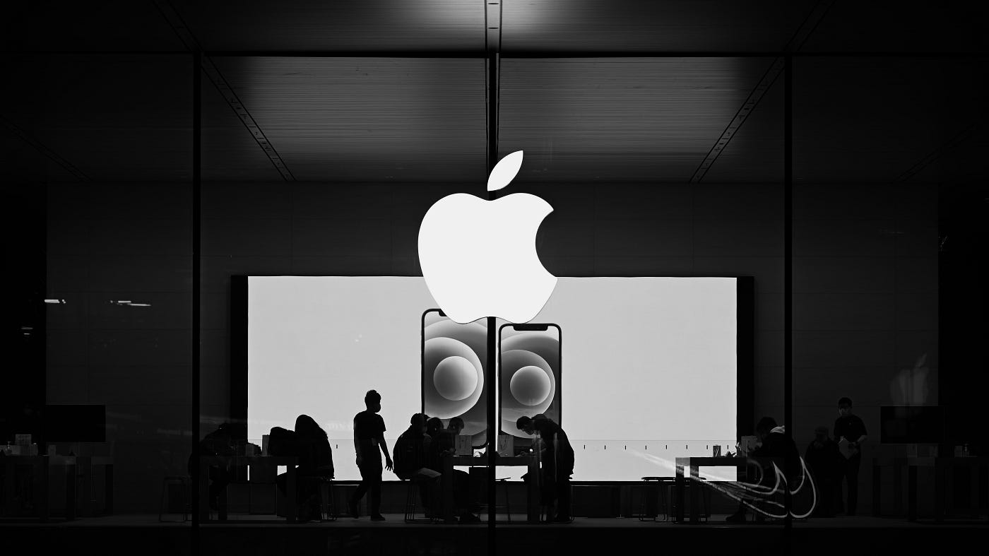 Apple Store interior with large Apple logo and people working inside.
