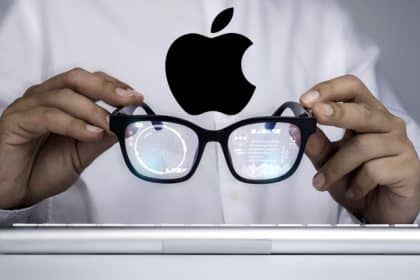Person holding Apple smart glasses with digital data reflected in the lenses.