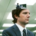 A man in a suit with a miniature version of himself working at a desk inside his head, from the show Severance.